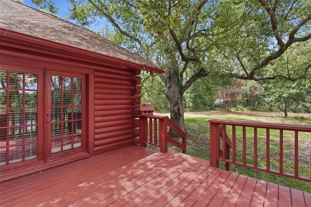 A red log cabin exterior features a wooden deck with railings and a large tree — 6409 CHISWICK COURT, NEW PORT RICHEY, FL