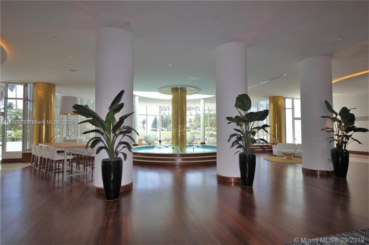 A spacious lobby features large white columns, dark wood floors, and a central circular fountain — 5161 Collins Ave # 210, Miami Beach FL 33140, MIAMI BEACH, FL