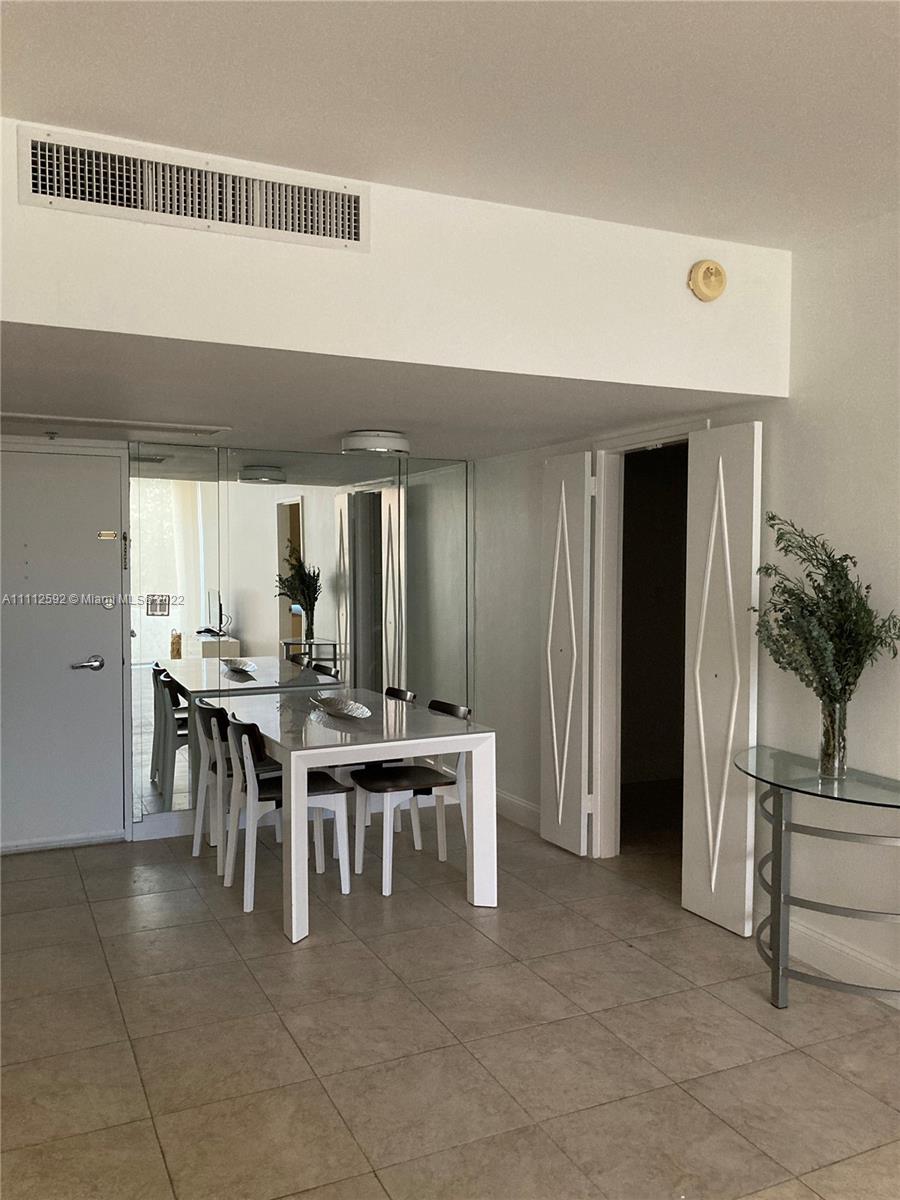 A dining area features a white table, chairs, mirrored walls, and tile flooring — 5161 Collins Ave # 210, Miami Beach FL 33140, MIAMI BEACH, FL