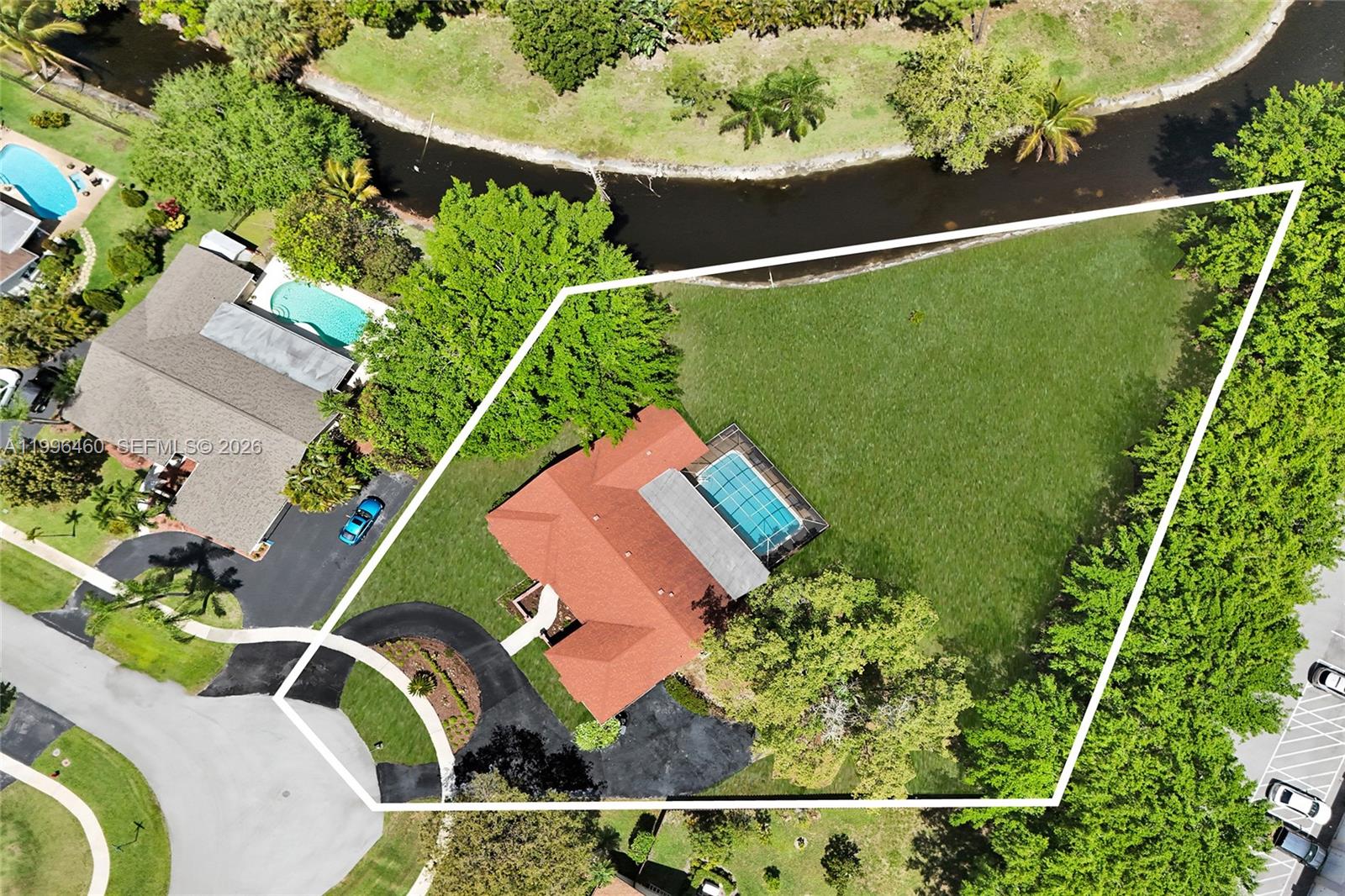 An aerial view shows a house with a pool and large yard beside a canal — 18428 S 102nd Way S, Boca Raton FL 33498, BOCA RATON, FL