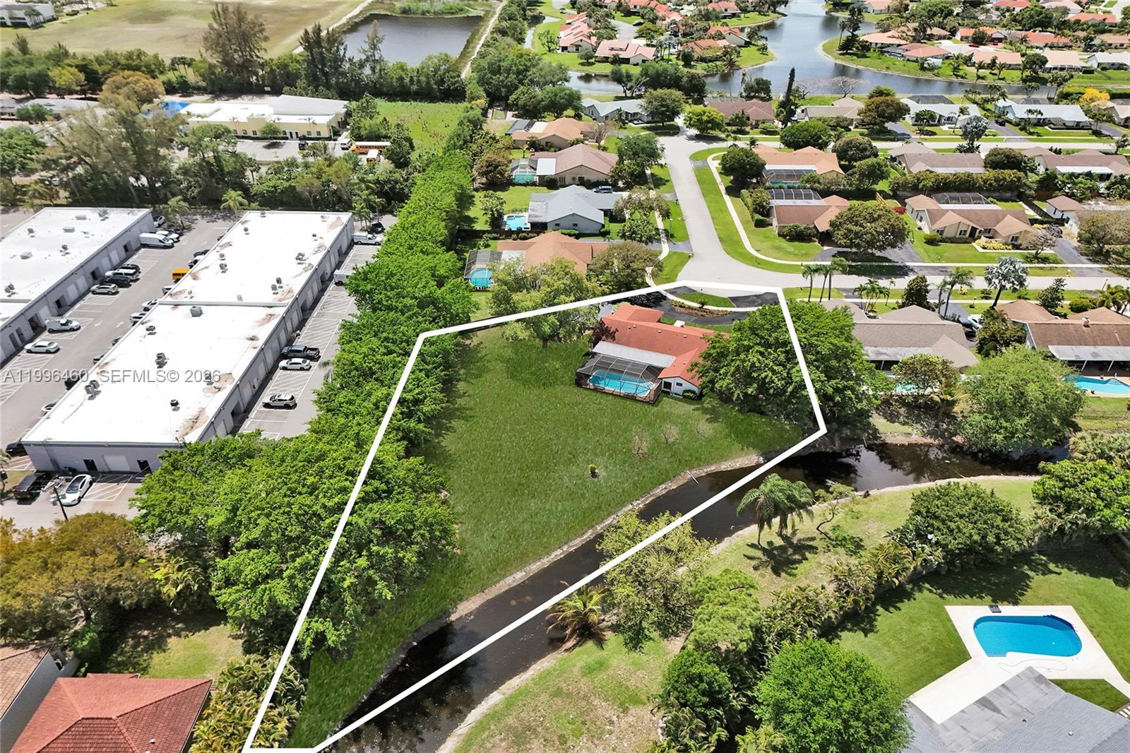 An aerial view shows a residential property with a large yard, pool, and canal — 18428 S 102nd Way S, Boca Raton FL 33498, BOCA RATON, FL