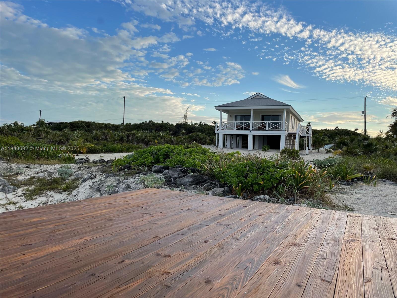A wooden deck overlooks a sandy landscape with a two-story house in the distance — 6892 GREAT HARBOUR DR, BH GH24440, BH