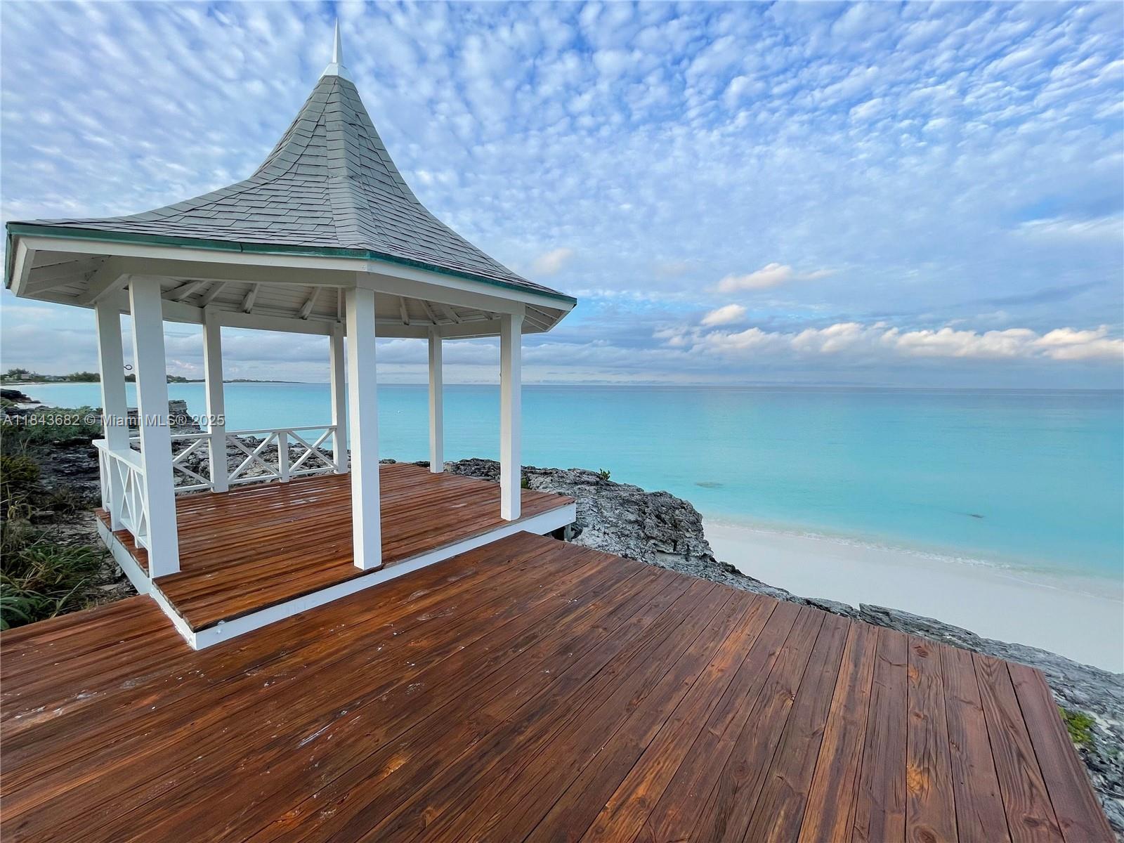 A wooden gazebo sits on a deck overlooking a rocky cliff and the ocean — 6892 GREAT HARBOUR DR, BH GH24440, BH