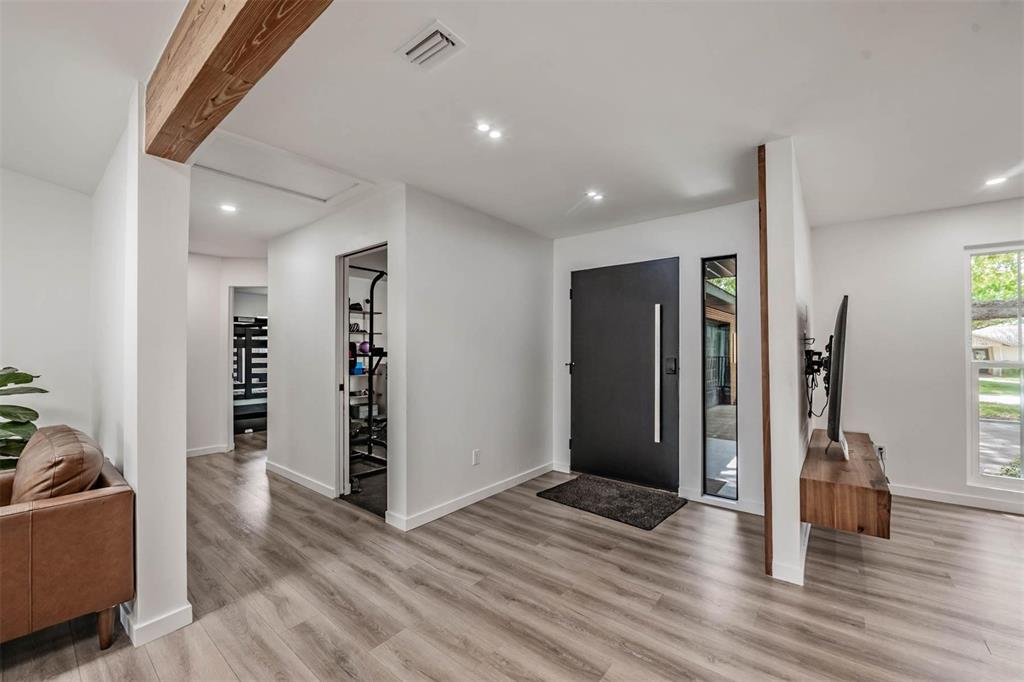 An entryway features a dark front door, wood-look flooring, and a wall-mounted television console — 848 HILLSIDE DRIVE, PALM HARBOR, FL