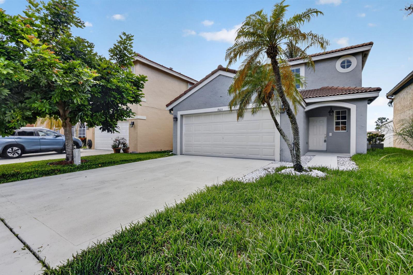 A two-story gray house with a two-car garage, a palm tree, and a concrete driveway — 7823 Springfield Lake Drive, Lake Worth FL 33467, LAKE WORTH, FL