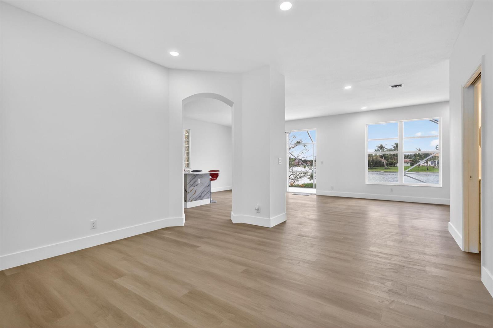 An empty room with light wood flooring, white walls, and a view of a lake — 7823 Springfield Lake Drive, Lake Worth FL 33467, LAKE WORTH, FL