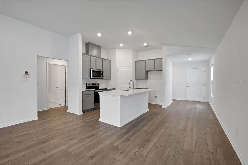A modern kitchen features gray cabinets, a white island, and wood-look flooring — 5712 LAGOON CRUISE WAY, JACKSONVILLE, FL
