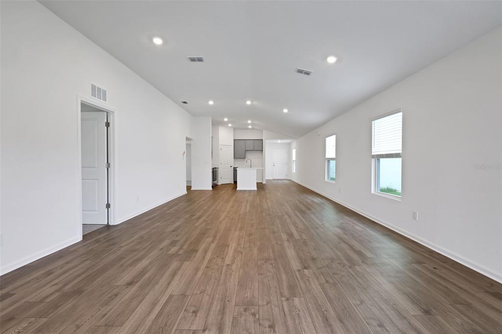An open-concept living area features white walls, recessed lighting, and wood-look flooring — 5712 LAGOON CRUISE WAY, JACKSONVILLE, FL
