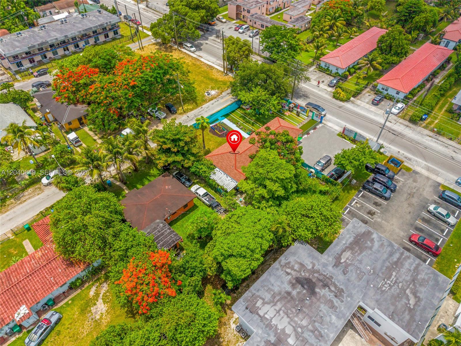 An aerial view shows a residential house with a red roof surrounded by lush trees — 111 NW 77th St, Miami FL 33150, MIAMI, FL