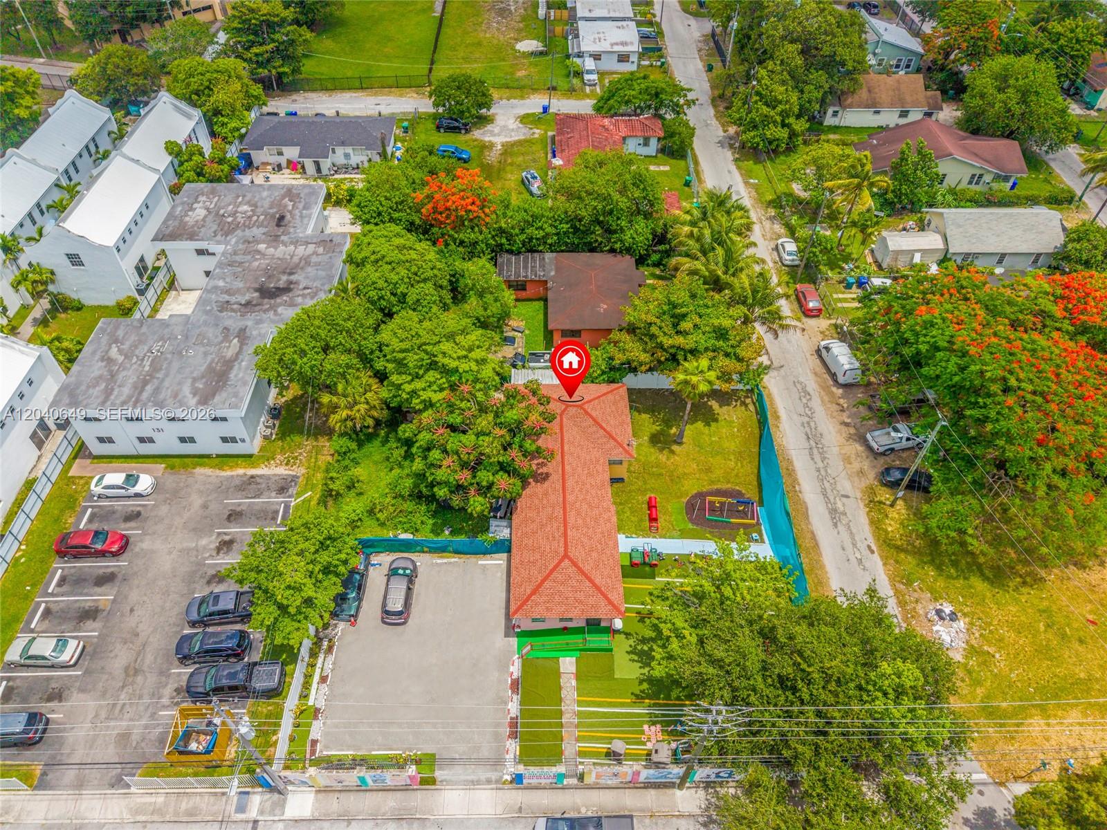 Aerial view of a residential property with a red-tiled roof and adjacent parking lot — 111 NW 77th St, Miami FL 33150, MIAMI, FL