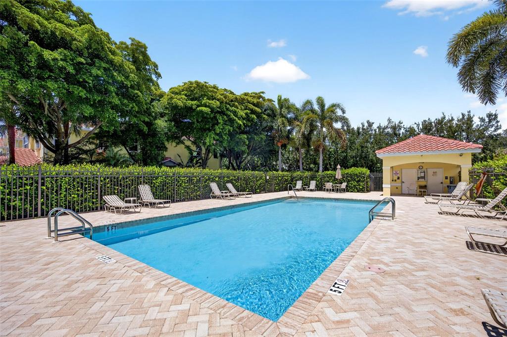 A rectangular swimming pool with a paved deck, lounge chairs, and a small cabana — 4400 LAZIO WAY UNIT 205, FORT MYERS, FL