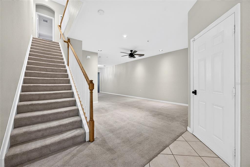An interior view shows a carpeted staircase with a wooden railing leading to a living area — 4400 LAZIO WAY UNIT 205, FORT MYERS, FL
