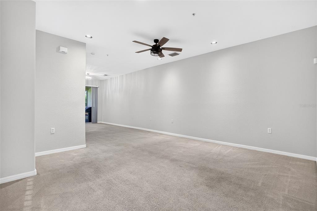 An empty living room features beige carpeting, light gray walls, and a ceiling fan — 4400 LAZIO WAY UNIT 205, FORT MYERS, FL