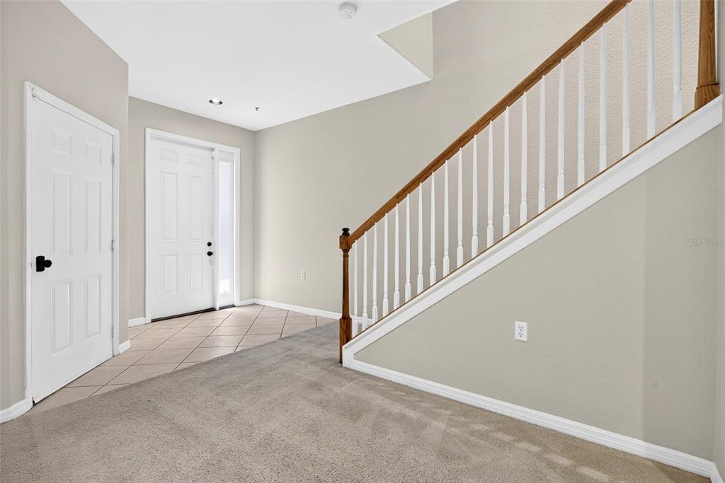 An entryway features a tiled floor, a carpeted staircase with a wooden railing, and two doors — 4400 LAZIO WAY UNIT 205, FORT MYERS, FL
