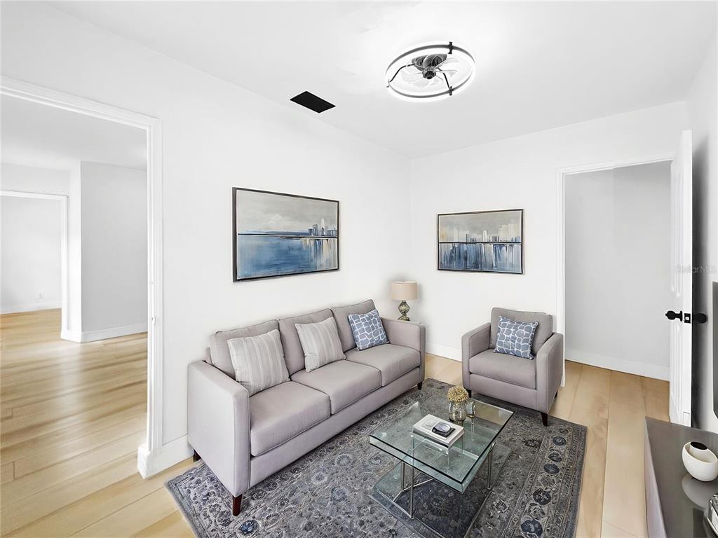 A living room features a gray sofa, matching armchair, glass coffee table, and two landscape paintings — 5021 9TH AVENUE S, GULFPORT, FL