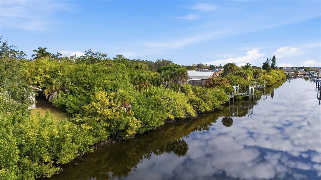 An aerial view shows a canal bordered by dense trees and a small residential structure — 12309 MITCHELL TERRACE, PORT CHARLOTTE, FL