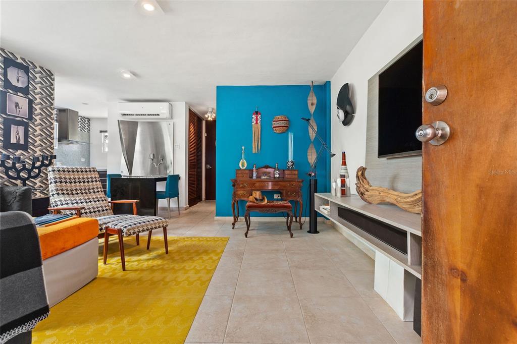 A living room features a bright blue accent wall, yellow rug, and a wooden console — 59 CALLE SAN MIGUEL UNIT 303, SAN JUAN, PR