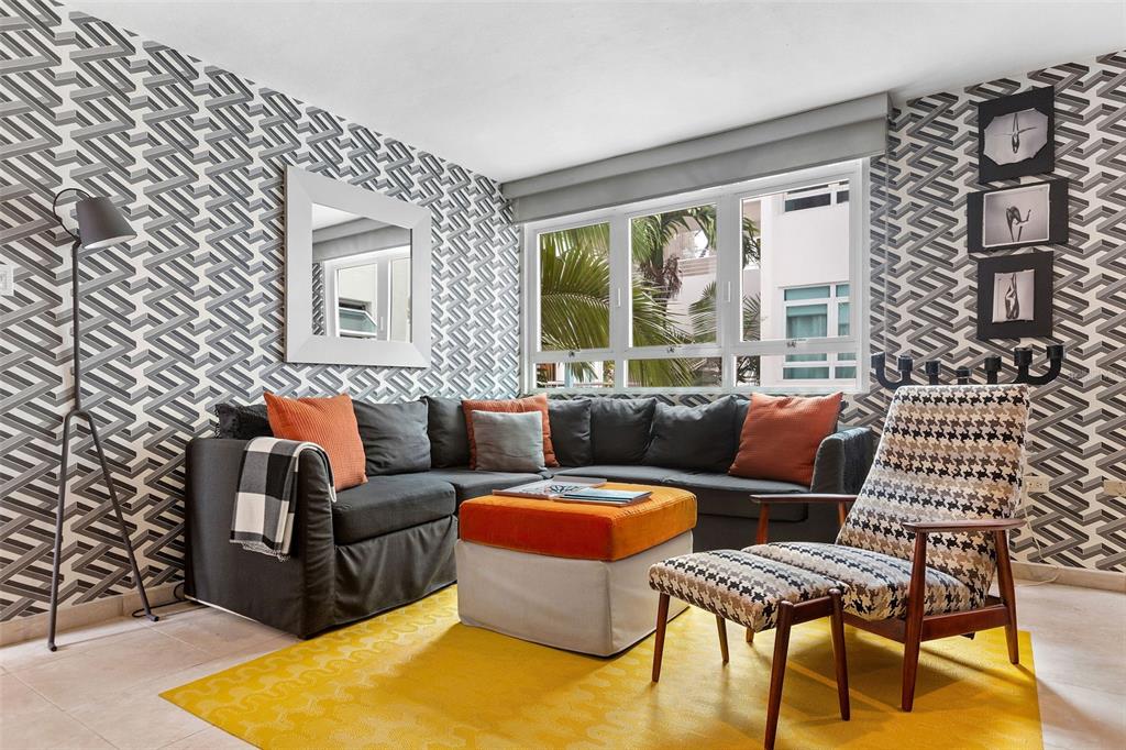 A living room features a gray sectional sofa, patterned wallpaper, and a bright yellow rug — 59 CALLE SAN MIGUEL UNIT 303, SAN JUAN, PR