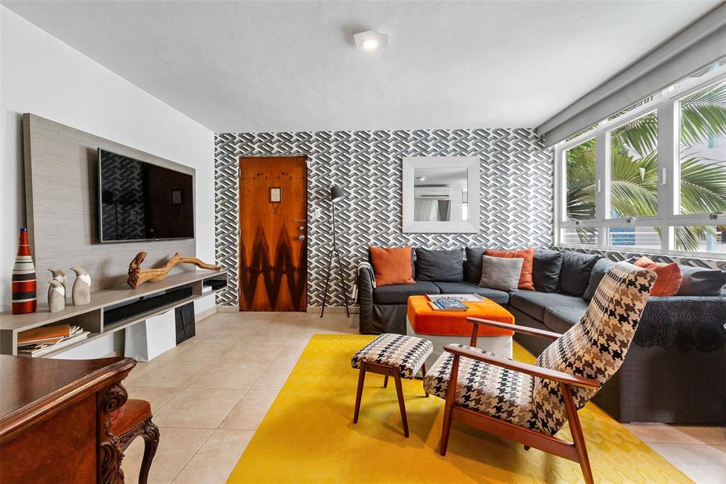 A living room features patterned wallpaper, a sectional sofa, a yellow rug, and a television — 59 CALLE SAN MIGUEL UNIT 303, SAN JUAN, PR