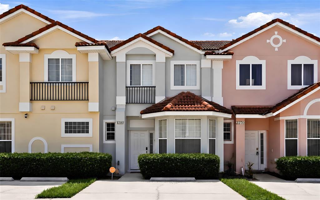 A row of three attached townhouses with stucco exteriors, tile roofs, and small front lawns — 1280 S BEACH CIRCLE, KISSIMMEE, FL
