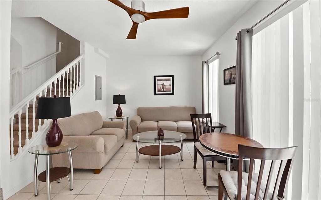 A living room features a staircase, two beige sofas, a glass coffee table, and dining area — 1280 S BEACH CIRCLE, KISSIMMEE, FL