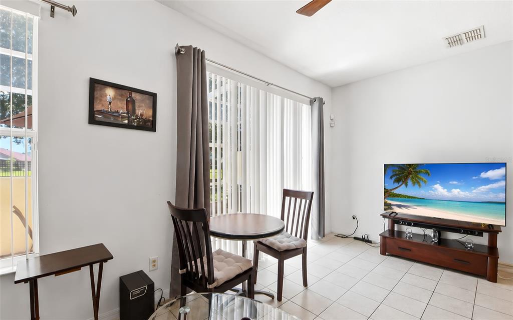 A living area features a dining table, chairs, a television on a stand, and tile flooring — 1280 S BEACH CIRCLE, KISSIMMEE, FL