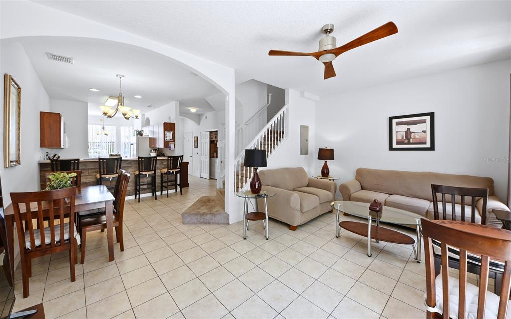 An open-concept living and dining area features tile flooring, a staircase, and a kitchen island — 1280 S BEACH CIRCLE, KISSIMMEE, FL