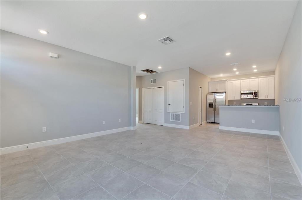An open-concept living area features light gray walls, tile flooring, and an adjacent kitchen — 1799 CORIANDER DRIVE UNIT 1799, KISSIMMEE, FL
