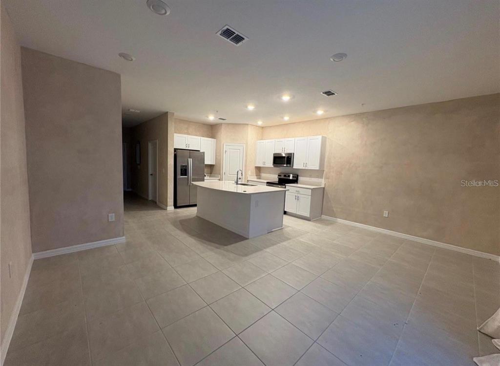 A kitchen with white cabinets, a central island, and light-colored tile flooring — 4840 REVOLUTIONARY WAY, ST CLOUD, FL