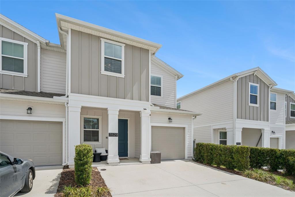 Two adjacent two-story townhomes feature beige siding, white trim, and attached single-car garages — 7629 DANUBE ROAD, KISSIMMEE, FL