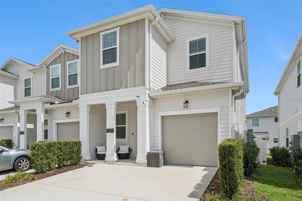 A two-story townhouse with light-colored siding, a single-car garage, and a small front porch — 7629 DANUBE ROAD, KISSIMMEE, FL