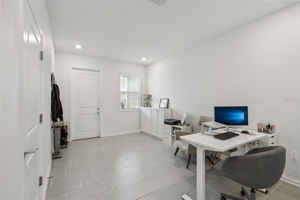 A home office with light gray tile flooring, a white desk, and a window — 7629 DANUBE ROAD, KISSIMMEE, FL