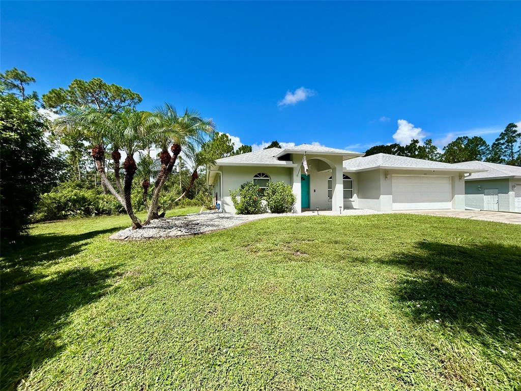 A single-story house with a light-colored exterior, a two-car garage, and a palm tree — 142 SOLANA STREET, NORTH PORT, FL