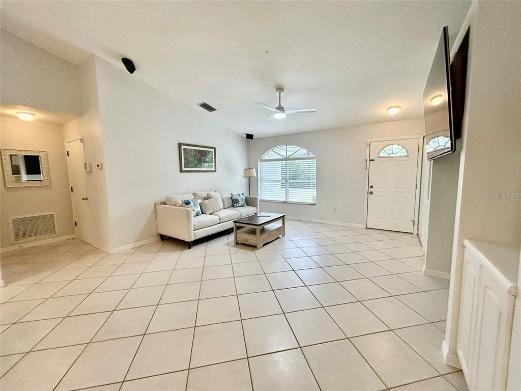 A living room features light-colored tile flooring, a white sofa, and a vaulted ceiling — 142 SOLANA STREET, NORTH PORT, FL
