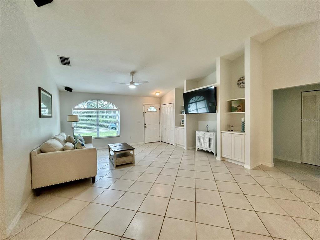 A living room features light tile floors, a white sofa, and a built-in media center — 142 SOLANA STREET, NORTH PORT, FL