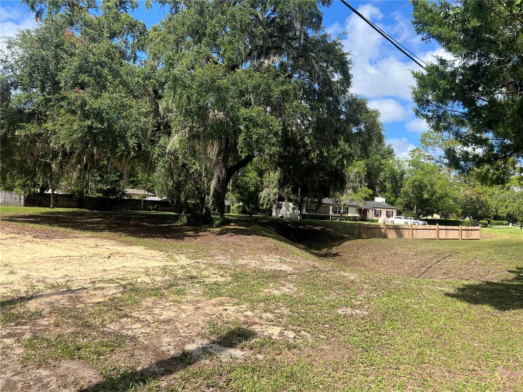 A large, grassy lot features a prominent oak tree and a wooden fence — 1456 SE 22ND AVENUE, GAINESVILLE, FL
