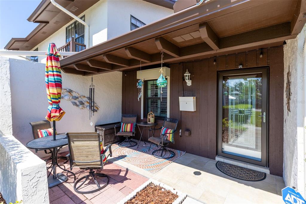 A covered patio features a dining set, two chairs, and a glass-paneled front door — 924 VIRGINIA AVENUE, ST CLOUD, FL