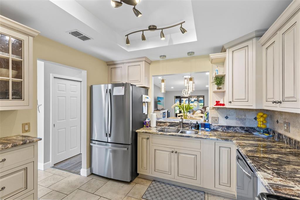 A kitchen features light-colored cabinets, stainless steel appliances, granite countertops, and a pass-through window — 924 VIRGINIA AVENUE, ST CLOUD, FL
