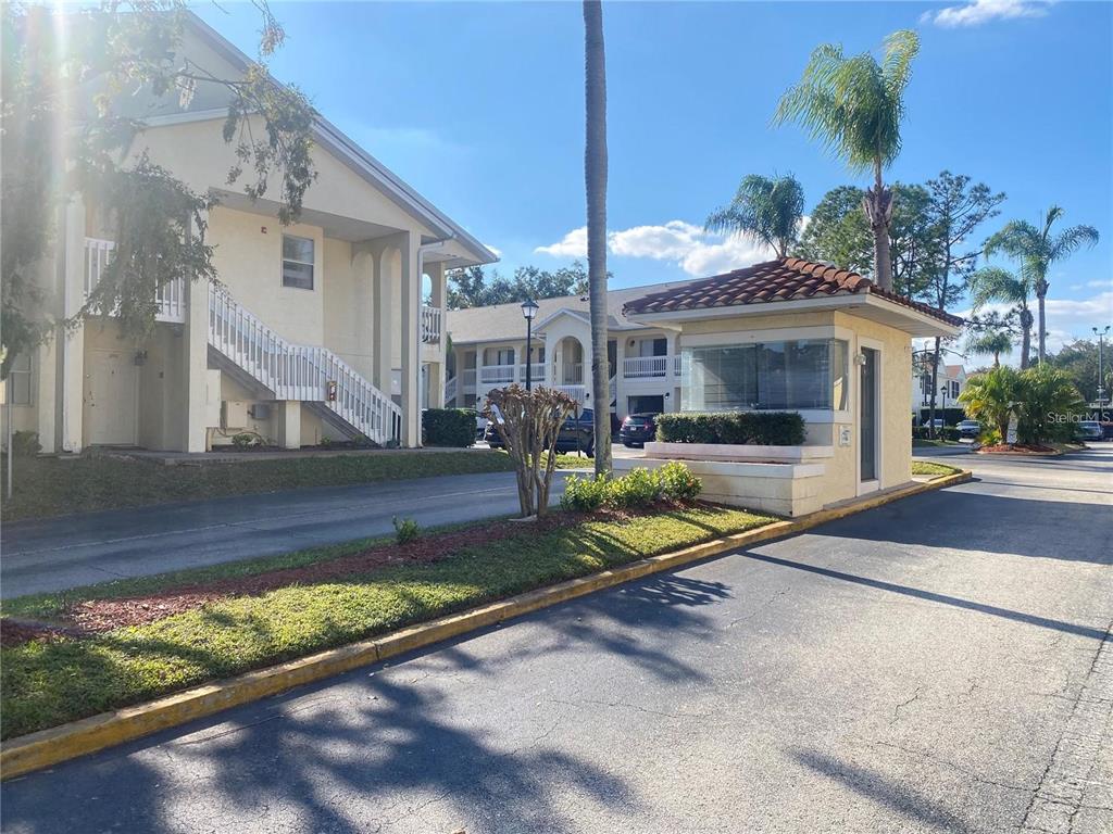 A guard shack sits at the entrance of an apartment complex with exterior staircases — 3204 SABAL PALMS COURT UNIT B, KISSIMMEE, FL