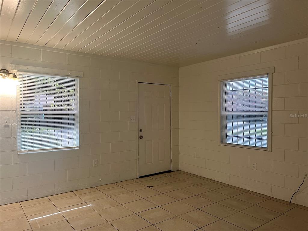 An interior room with white painted block walls, tiled floors, and two windows — 709 BOSTON AVENUE, ORLANDO, FL
