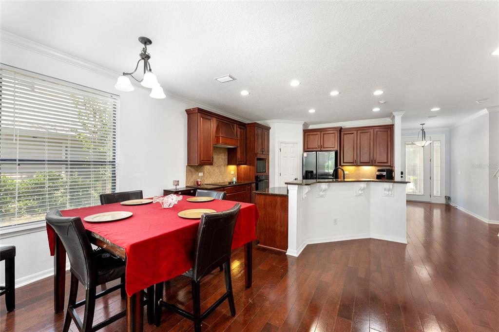 A dining area with a red-clothed table sits adjacent to a kitchen with dark cabinetry — 4444 NW 82ND ROAD, GAINESVILLE, FL
