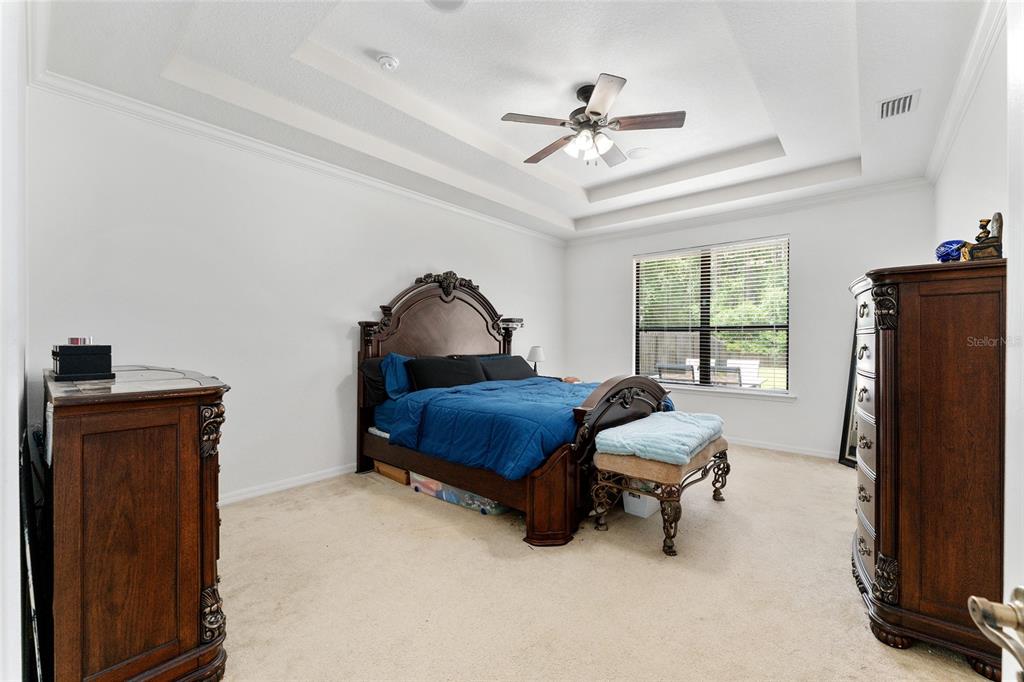 A bedroom features a tray ceiling, a dark wood bed frame, and two matching dressers — 4444 NW 82ND ROAD, GAINESVILLE, FL