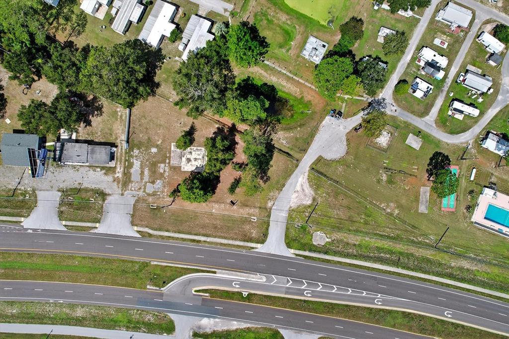 This aerial view shows a vacant lot with trees and gravel driveways near a highway — 15541 CORTEZ BOULEVARD, BROOKSVILLE, FL