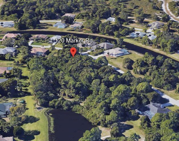 An aerial view shows a wooded residential lot surrounded by houses and a canal — 120 Marker Road, FL 33947, FL