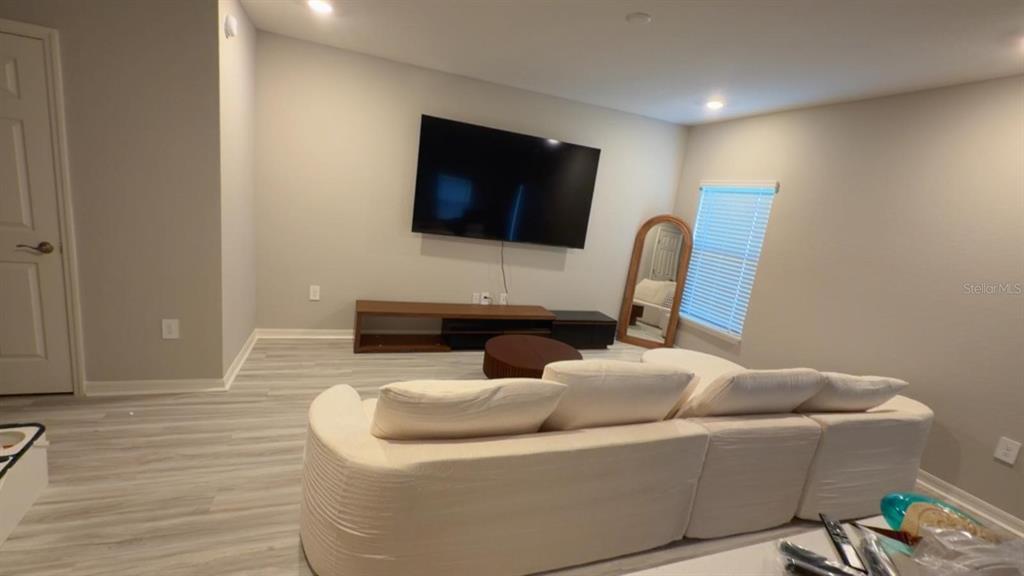 A living room features a large wall-mounted television, a low media console, and a sectional sofa — 5117 SYLAS JAX AVENUE, WINTER HAVEN, FL