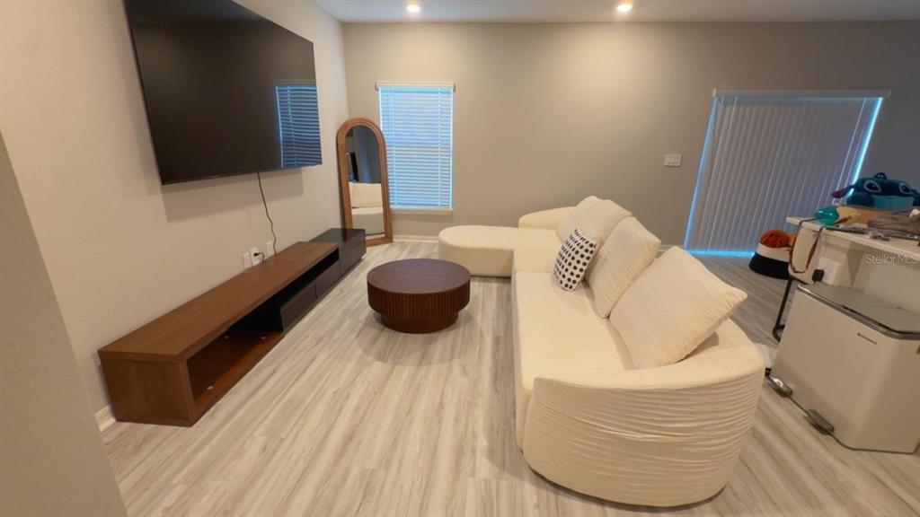 A living room features a large television, a wooden media console, and a white sectional — 5117 SYLAS JAX AVENUE, WINTER HAVEN, FL