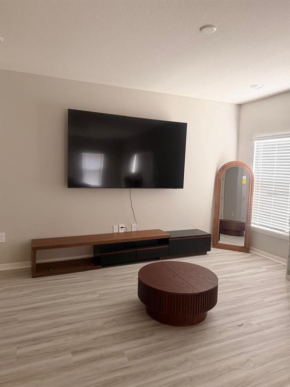 A living room features a wall-mounted television, a low media console, and a round table — 5117 SYLAS JAX AVENUE, WINTER HAVEN, FL