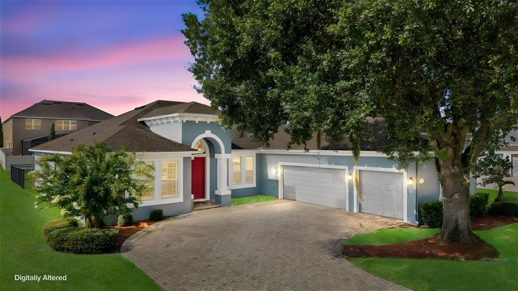 A blue single-story house with a red front door, three-car garage, and a paved driveway — 2100 MISTY GLEN DRIVE, APOPKA, FL