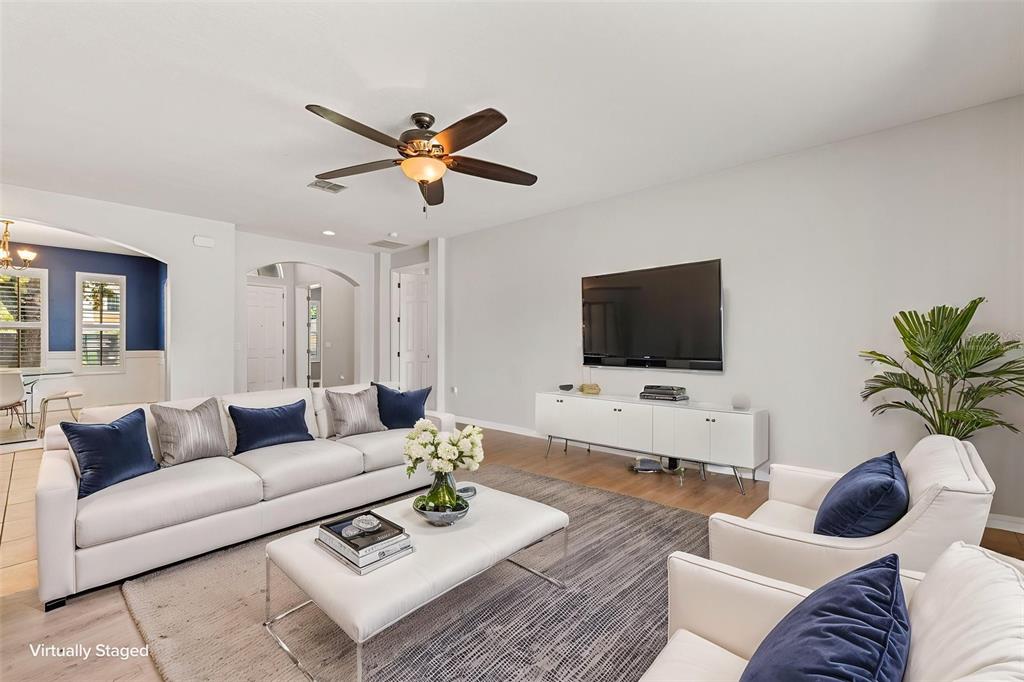 This living room features a white sofa, two armchairs, a television, and a ceiling fan — 2100 MISTY GLEN DRIVE, APOPKA, FL