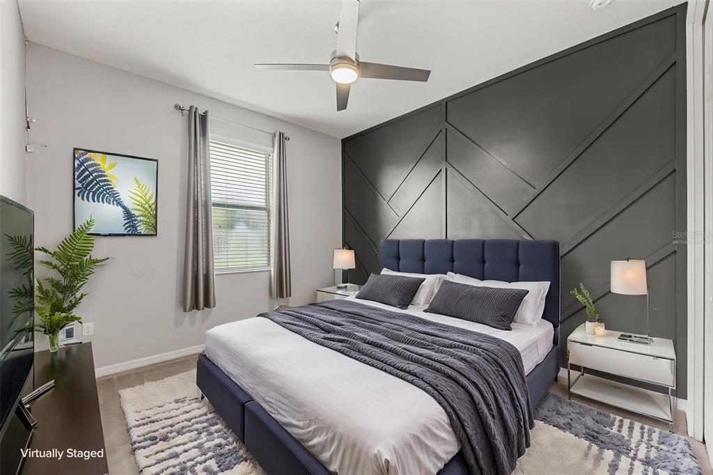 A bedroom features a dark blue upholstered bed against a geometric charcoal accent wall — 2100 MISTY GLEN DRIVE, APOPKA, FL